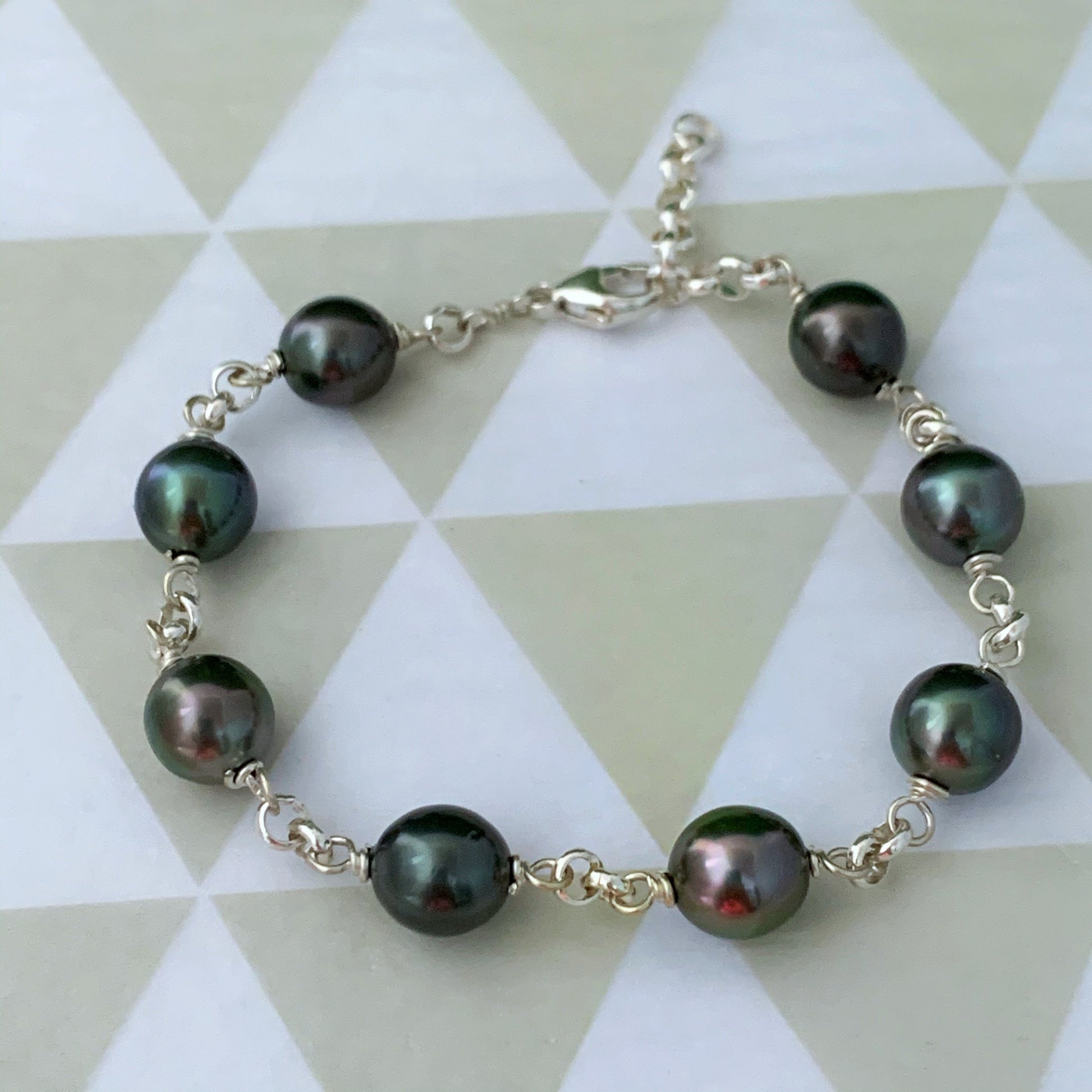 Tahitian pearl bracelet in sterling silver featuring 7 to 8 lustrous dark pearls, wire-wrapped and linked with a thick, elegant chain.
