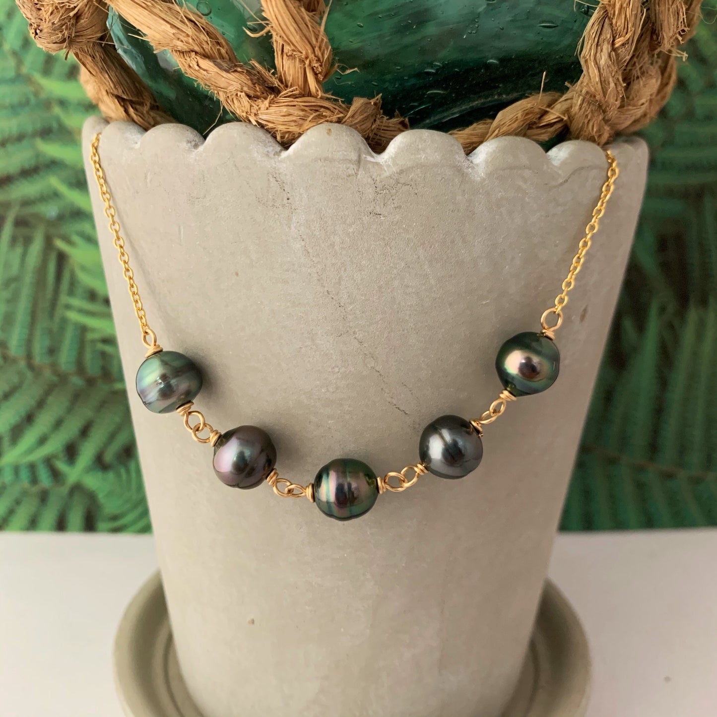 14k yellow gold-filled necklace with five black Tahitian pearls evenly spaced on a delicate chain.