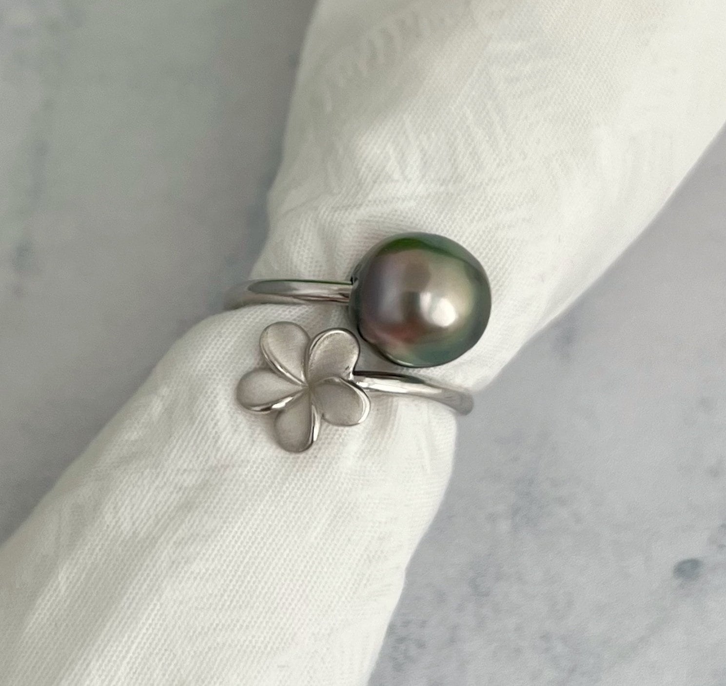 Sterling silver wrap ring featuring a lustrous Tahitian pearl and a plumeria flower.