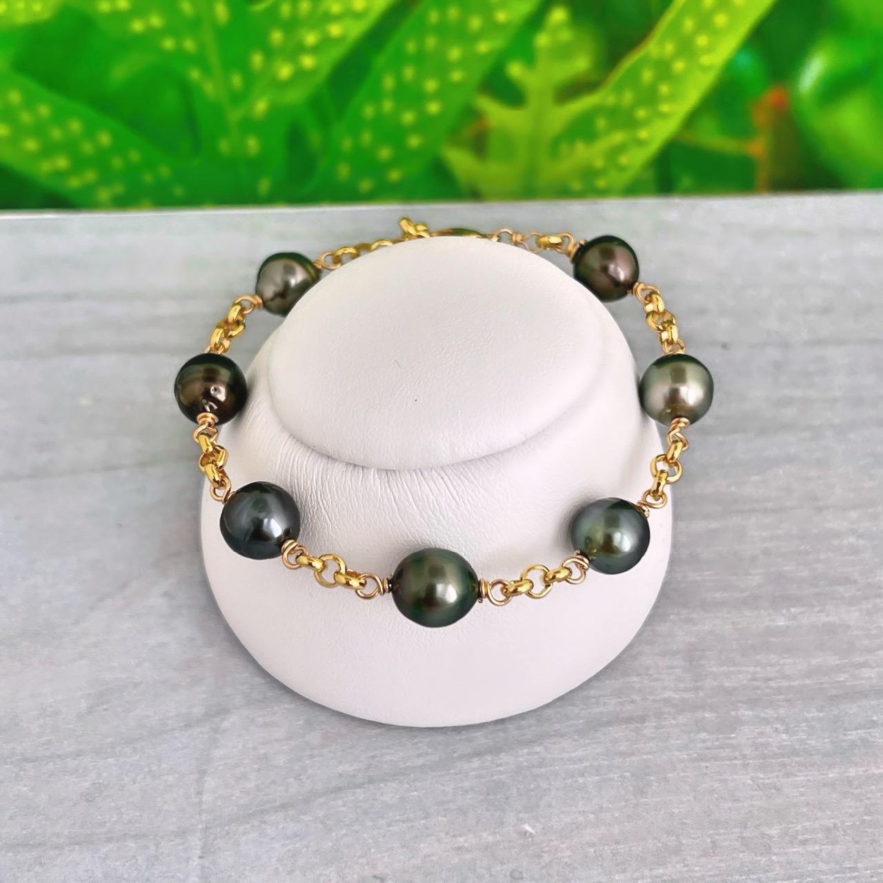 Tahitian pearl bracelet in Gold filled featuring 7 to 8 lustrous dark pearls, wire-wrapped and linked with a thick, elegant chain.
