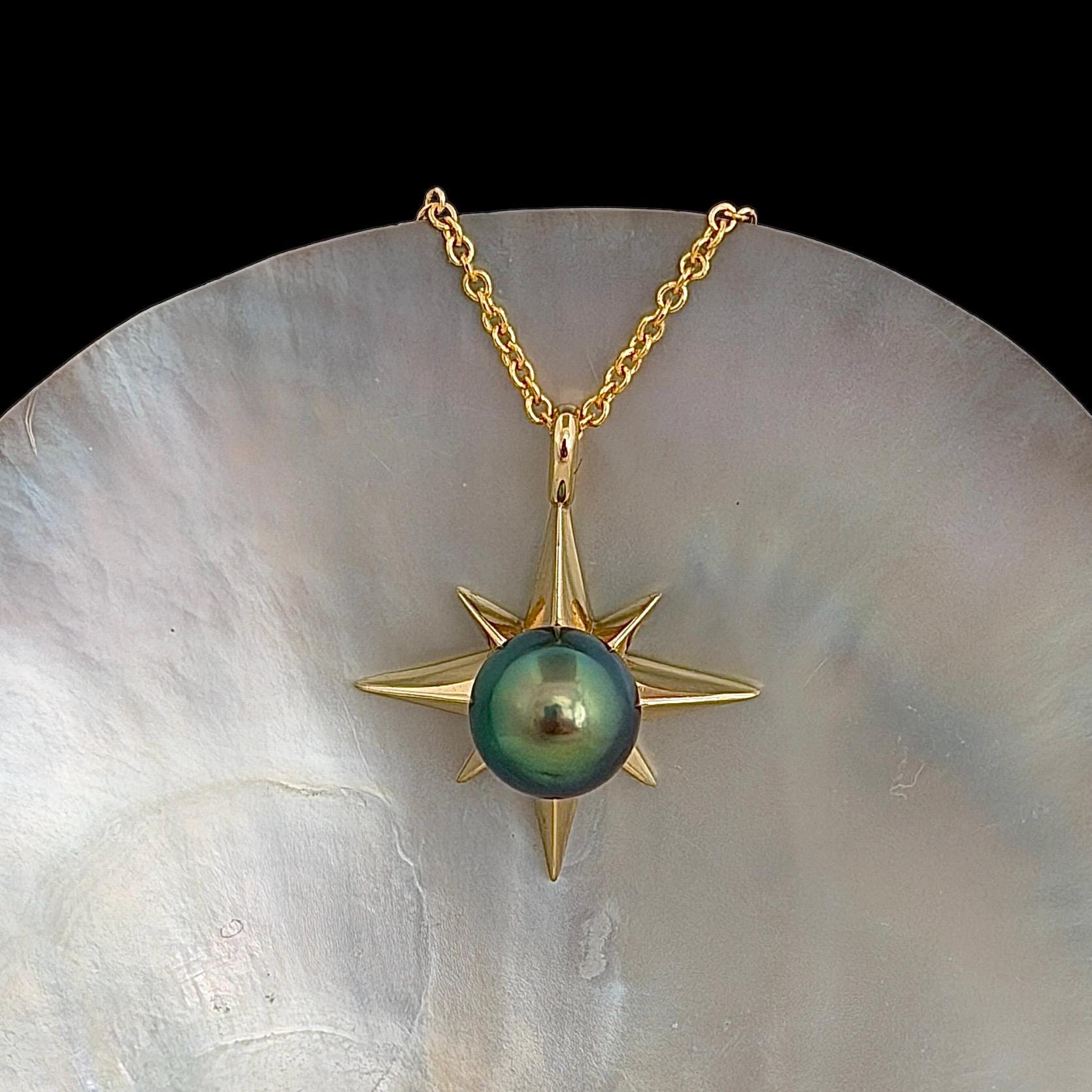 A gold-colored necklace featuring a starburst pendant with a vibrant blue green, round center stone. The pendant is suspended from a delicate chain.